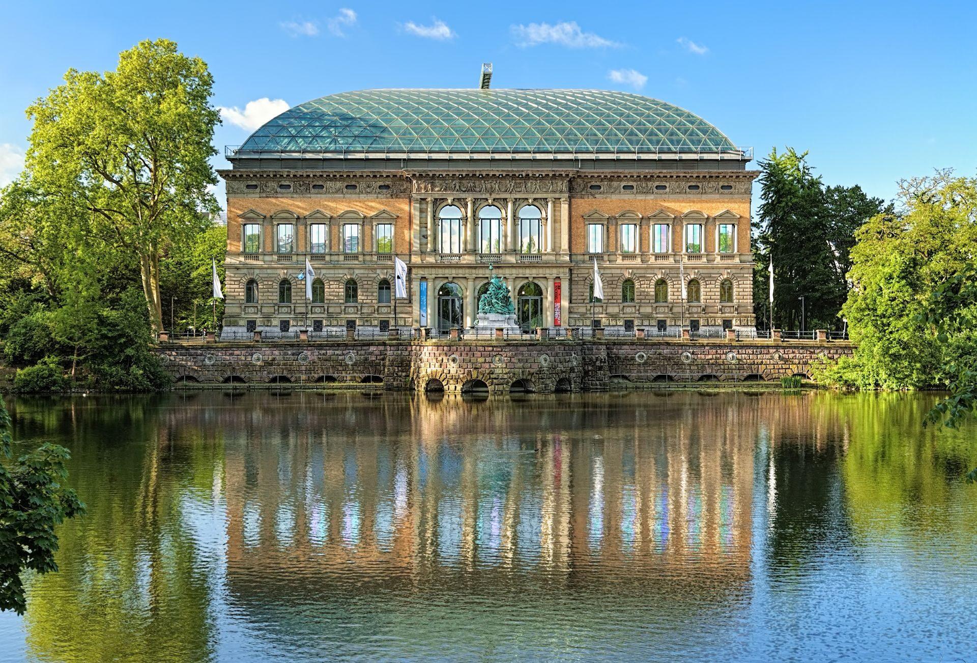 Kunstmuseum K20 in Duesseldorf mit Glasdach und klassischer Fassade, spiegelt sich im Wasser